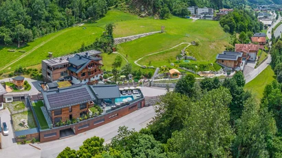 Luftaufnahme eines Hotels mit Solarpanelen und Pool in grüner Berglandschaft
