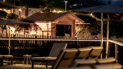 Beleuchtete Liegestühle und Holzhütte bei Nacht in den Bergen
