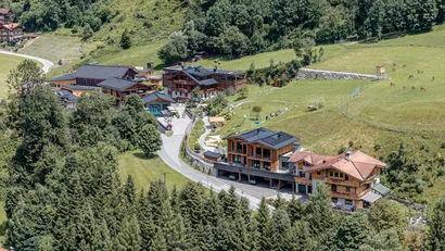 Bergdorf mit Chalets und grünen Wiesen umgeben von Wald