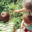 Erwachsener und zwei Kinder betrachten Pflanzen in einem Garten