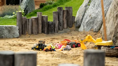 Sandkasten mit Spielzeugfahrzeugen und Holzeinfassung im Garten